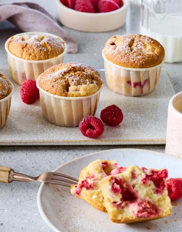 Einfache Himbeer Muffins mit frischen Himbeeren drum herum.