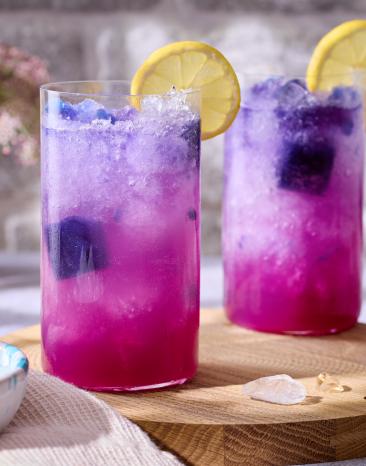 Butterfly Pea Tee Slush - pinkes Getränk in Gläsern mit Zitronenscheiben.