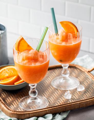 Aperol Slush mit Orangenscheiben in zwei Gläsern.