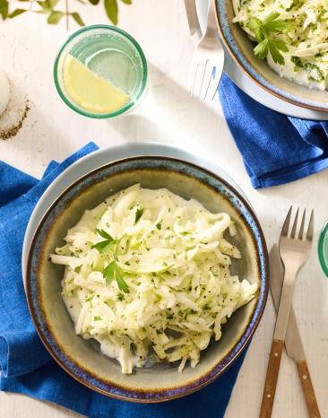 Kohlrabi Salat in Schalen auf einem gedeckten Tisch.