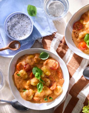 One-Pot-Gnocchi Tomate-Mozzarella in Schüsseln auf einem gedeckten Tisch.