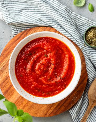 Pizzasauce in einer weißen Schale mit Basilikum.