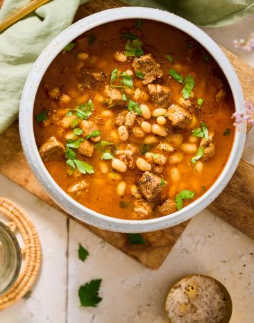 Bohneneintopf mit Rind (Kuru Fasulye) in einem Suppenteler mit goldfarbenem Löffel.