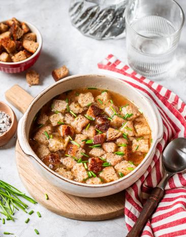 Brotsuppe mit Brotwürfeln in einer hellen Schüssel.