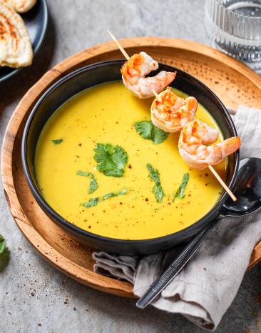 Mango-Curry-Suppe mit Garnelenspieß in einem Suppenteller.