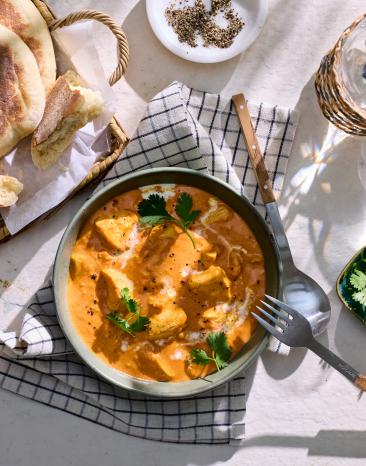 Butter Chicken mit Naan Brot auf einem gedeckten Tisch.