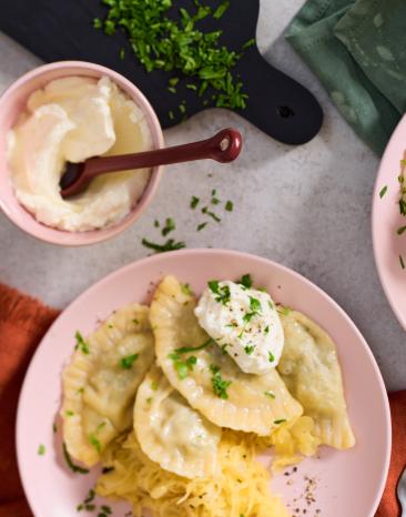 Pierogi mit Sauerkraut gefaltete Teigtaschen auf rosa Tellern.