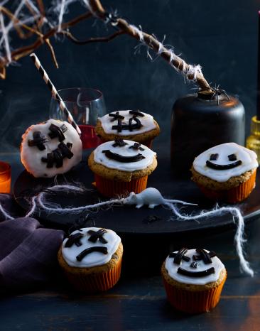 Skelett-Muffins mit weißem Zuckerguss und gruseligen Gesichtern.