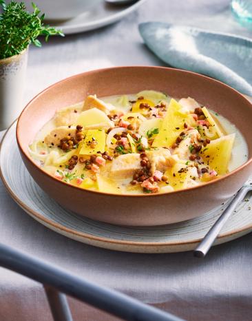 Steckrüben-Pastinaken-Eintopf mit Hähnchen in einem tiefen Teller.