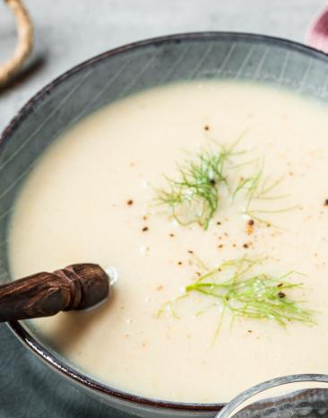 Fenchelsuppe mit Kräutern garniert in dunklen Schüsseln