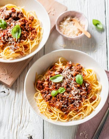 Einfache Spaghetti Bolognese auf Tellern garniert mit Basilikum