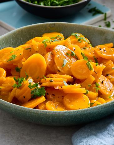 Glasierte Karotten mit Kräutern in einer Schüssel.