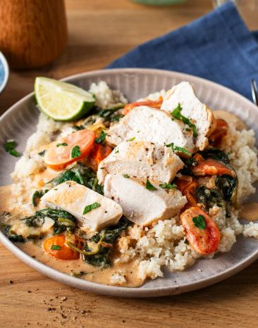 Parmesan Hähnchen mit Blumenkohlreis auf einem Teller.