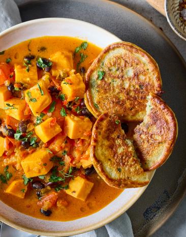 Süßkartoffel Curry mit Kokosmilch und Pancakes in einer weißen Schüssel.