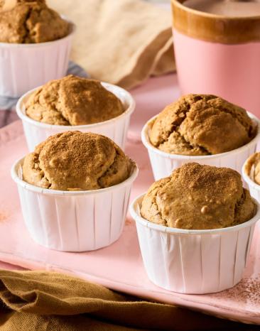 Zuckerfreie Muffins in Papierförmchen auf rosa Tablett.