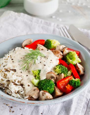 Wildreis mit Gemüse und Forellen-Frischkäse-Sauce auf einem Teller.