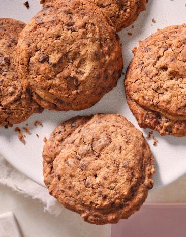 Klassische Chocolate Chip Cookies auf einem Teller mit Krümeln.