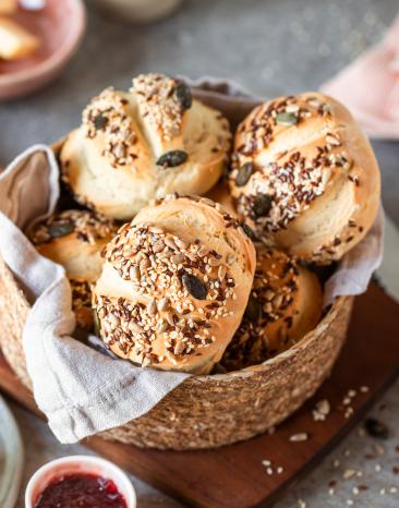 Selbstgemachte Brötchen mit Körnern und Samen in einem Brotkorb.