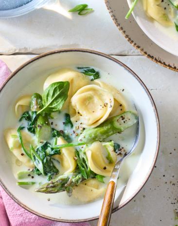 Tortellini-Suppe mit grünem Spargel in einer Schüssel.