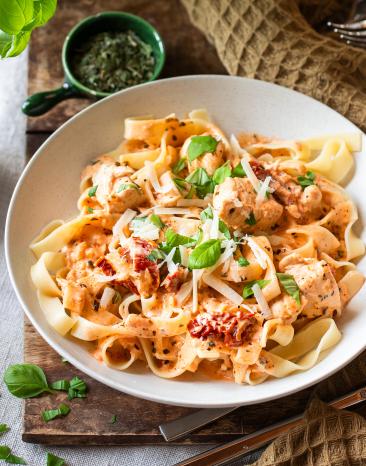 Fettuccine mit Hähnchen und getrockneten Tomaten in Schüsseln.