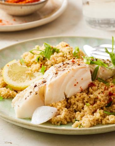 Kabeljaufilets mit Couscous hübsch auf einem Teller angerichtet.