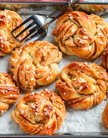Schwedische Zimtknoten (Kanelbullar) auf einem Blech mit Backpapier.