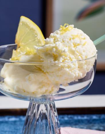 Zitroneneis in Glasschälchen mit frischen Zitronenscheiben garniert.