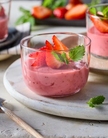 Erdbeerpudding mit frischen Erdbeeren und Minze garniert in Glasschälchen angerichtet.