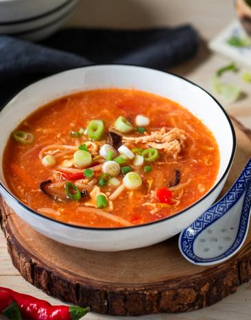 Pekingsuppe mit Hähnchen in einer Schüssel mit Lauchzwiebeln garniert.