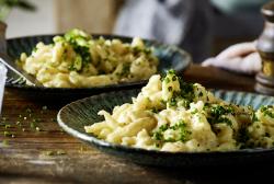 Käsespätzle angerichtet auf einem rustikal gedeckten Tisch