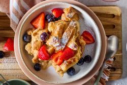 Zwiebackschmarrn mit Puderzucker und frischen Beeren in einem Teller.